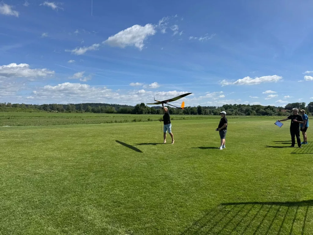 Starthelfer wirft ein Segelflugmodell, daneben der Pilot mit Fernsteuerung und ein Zeitnehmer