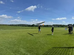 Starthelfer wirft ein Segelflugmodell, daneben der Pilot mit Fernsteuerung und ein Zeitnehmer
