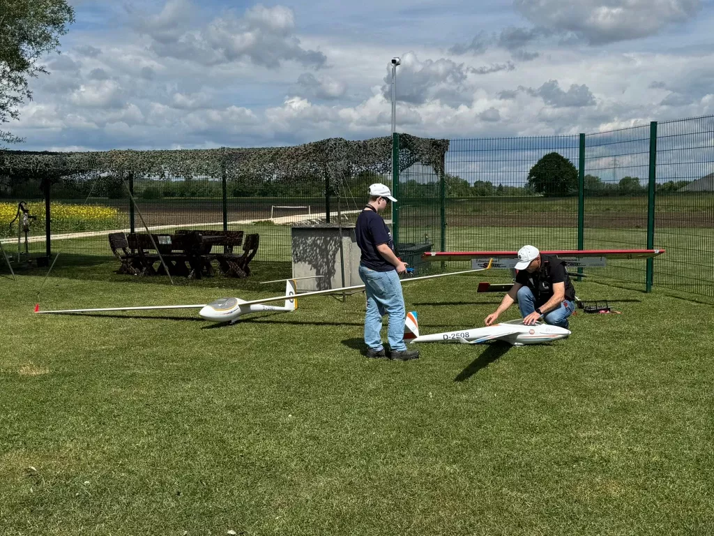 Zwei Modellflieger bereiten ihre Segelflugmodelle auf der Wiese für den Schlepp vor