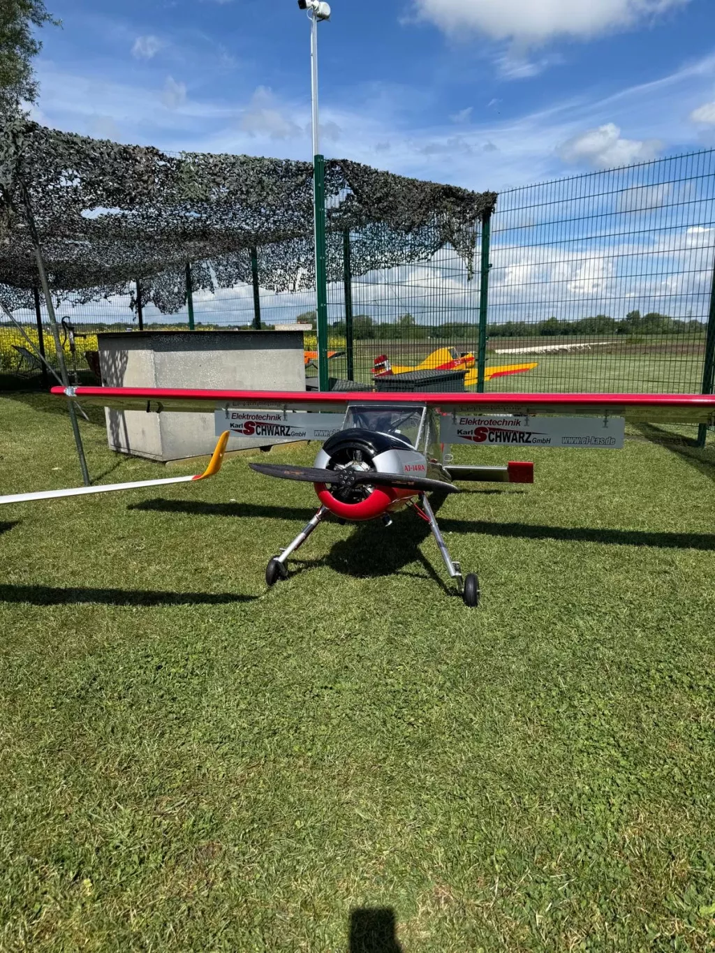 Rot-weißes Motormodell mit Sternmotor von vorne, dahinter ein gelbes Schleppflugzeug