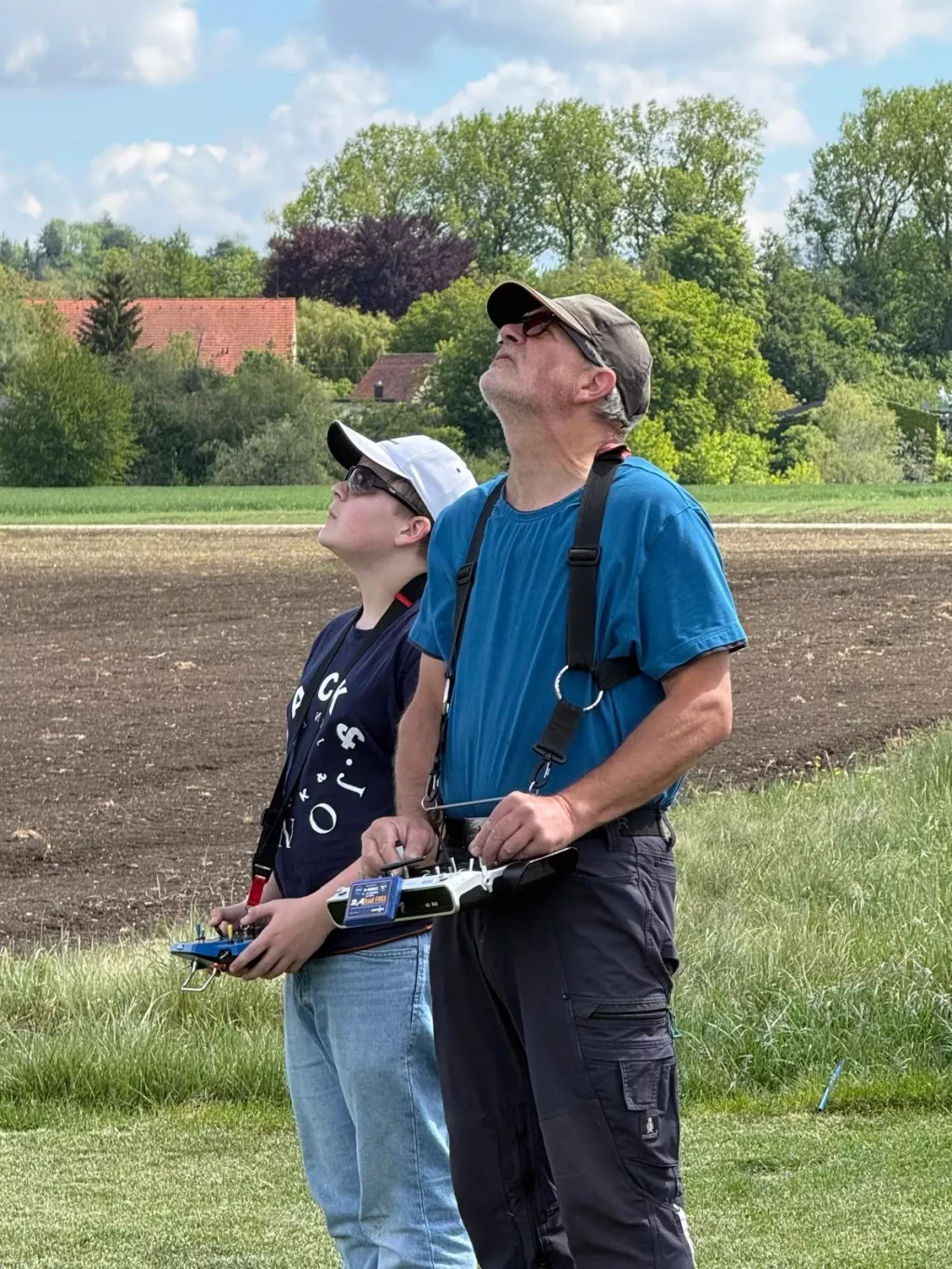 Ein Jugendlicher und ein erwachsener Pilot verfolgen mit ihren Fernsteuerungen den Flug