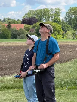 Ein Jugendlicher und ein erwachsener Pilot verfolgen mit ihren Fernsteuerungen den Flug