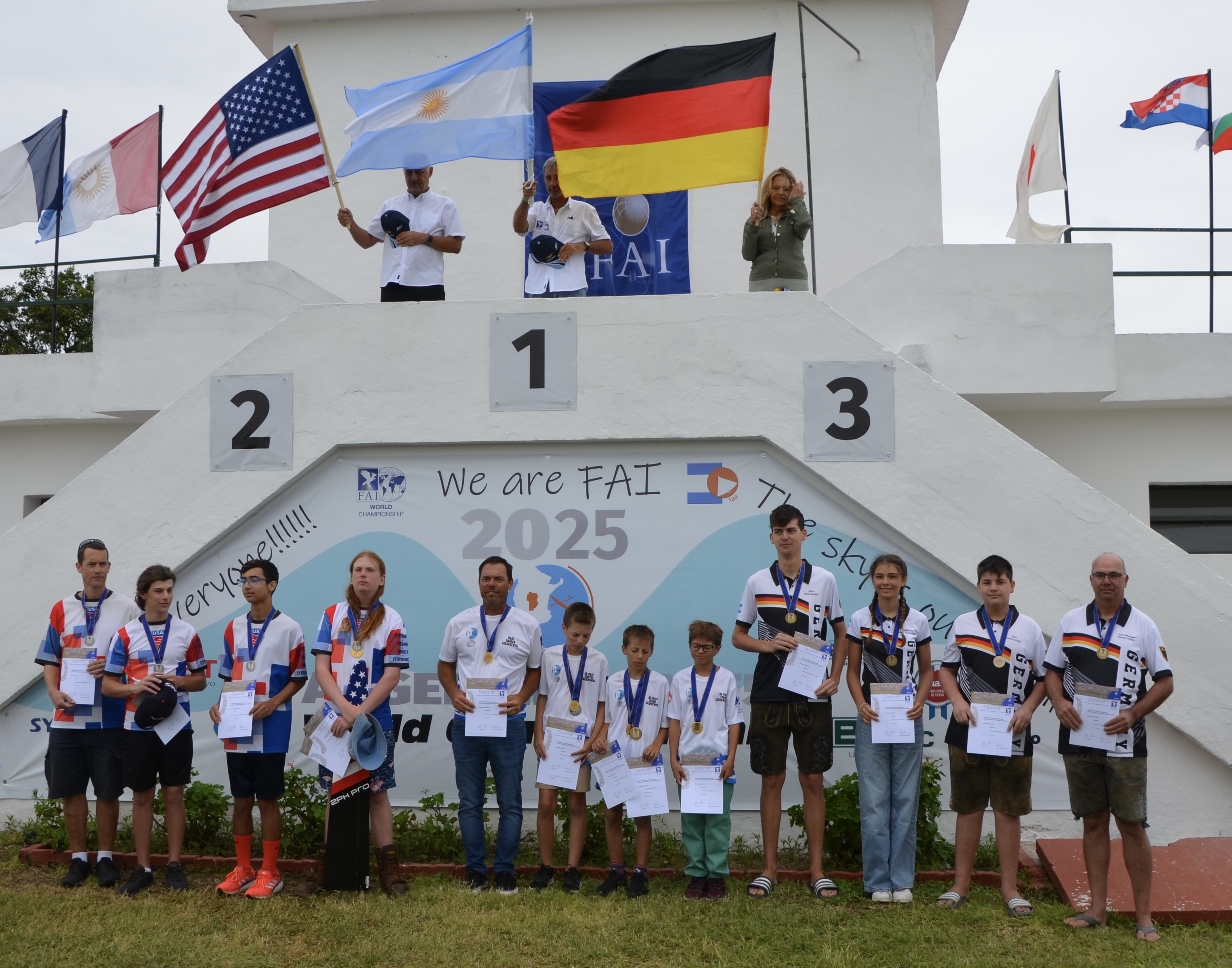 Siegerehrungspodium der F5J-Weltmeisterschaft 2025 in Argentinien mit Teilnehmern verschiedener Altersklassen und Nationalflaggen