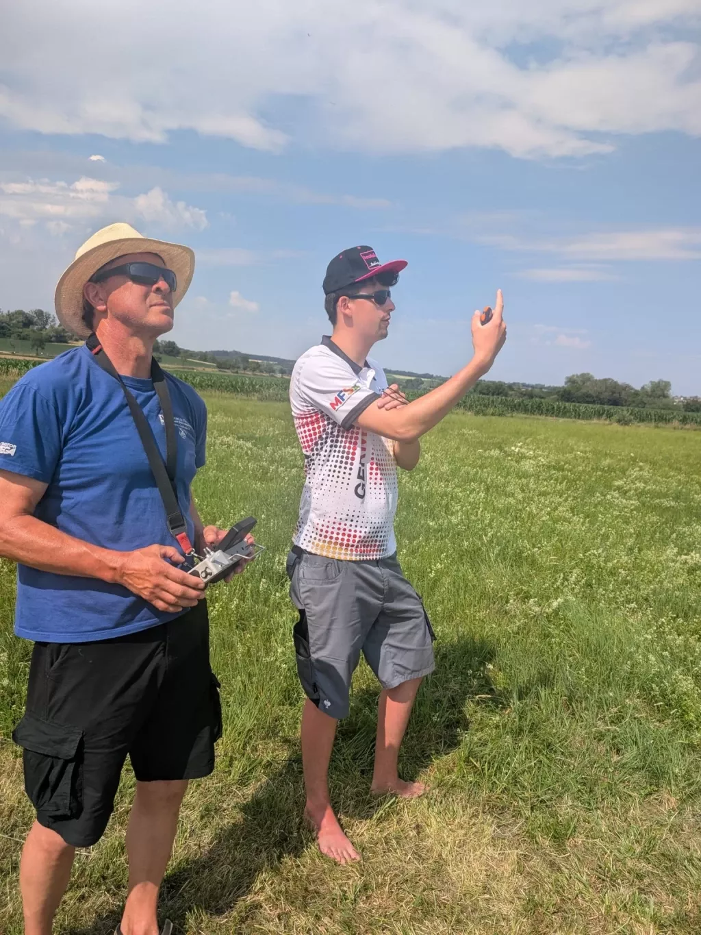 Pilot mit Fernsteuerung und ein Helfer im Wettbewerbstrikot beobachten den Himmel