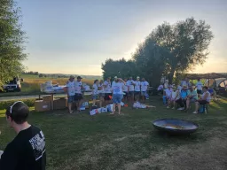 Helfer und Gäste bei Sonnenuntergang, im Vordergrund eine große Feuerpfanne