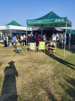 Grüne Pavillons mit Liegestühlen, dahinter warten Gäste an der Essensausgabe