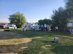 Abendliche Runde auf dem Vereinsgelände mit Tischen, Bänken und Feuerschale