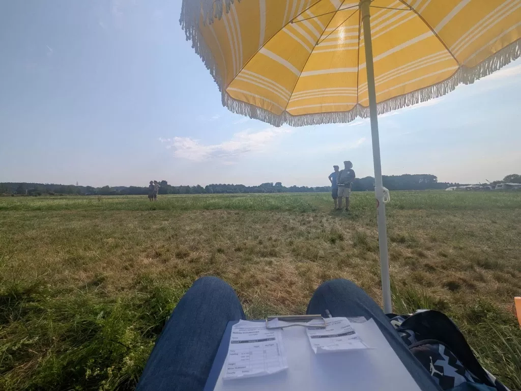 Blick vom Zeitnehmerplatz unter dem Sonnenschirm über das Flugfeld, davor die Wertungsbögen