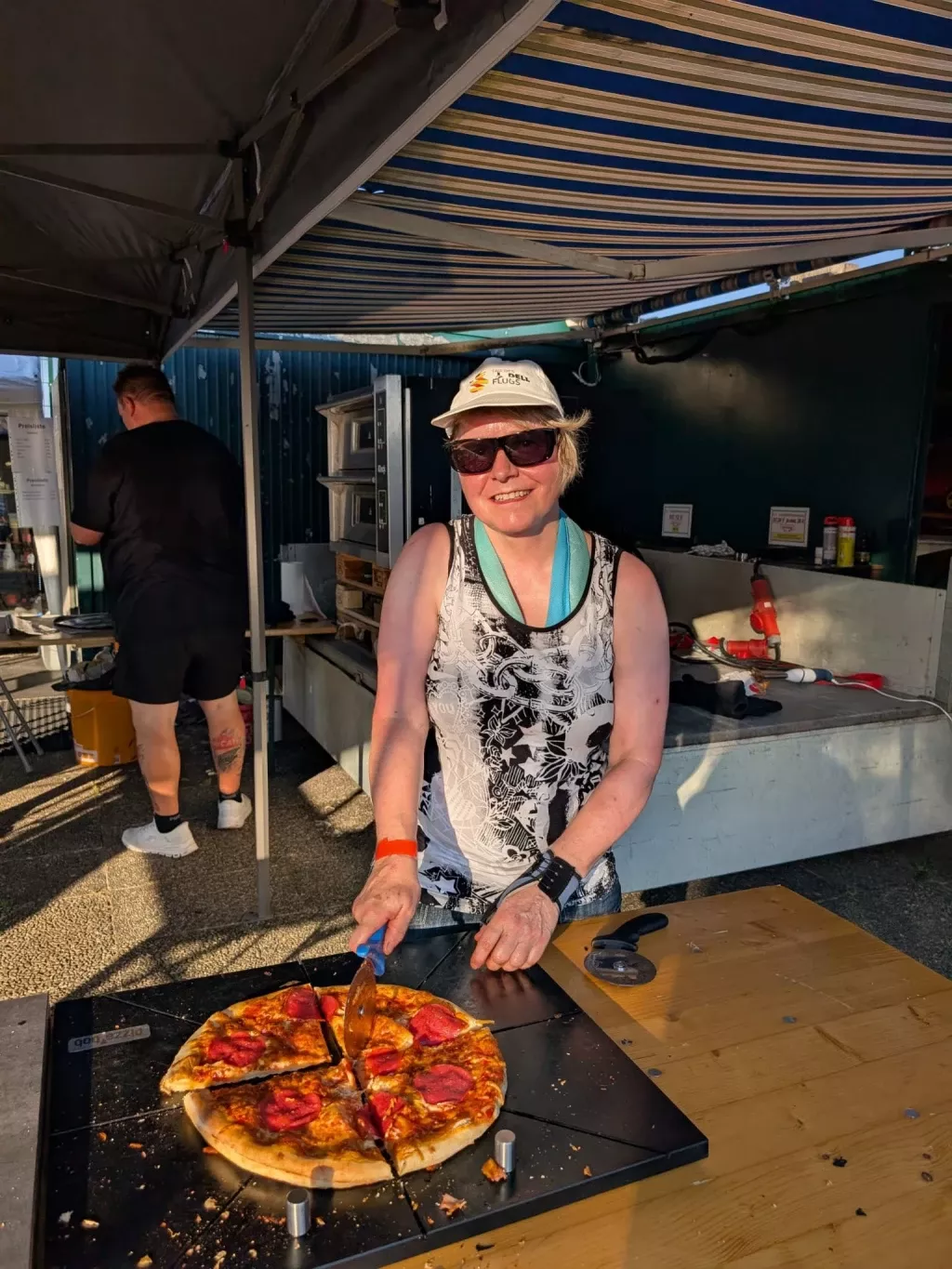 Eine Helferin schneidet eine frisch gebackene Pizza an der Essensausgabe