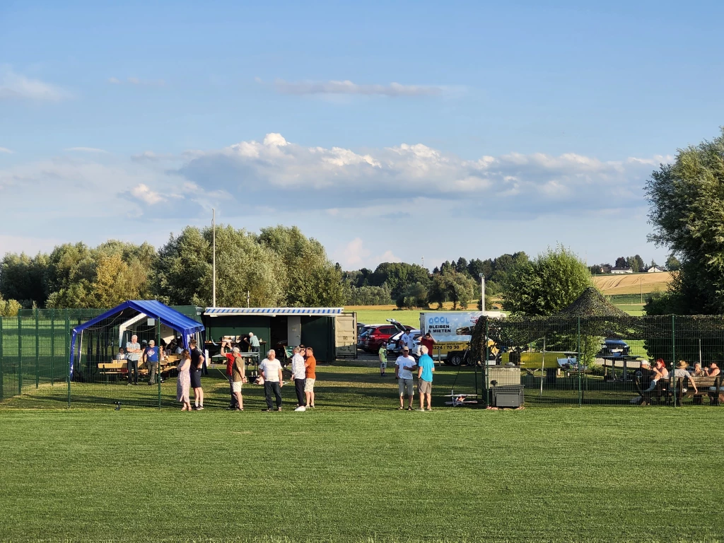 Modellflugverein Sommerfest mit blauen Pavillons, Besuchern und gr&uuml;ner Rasenfl&auml;che bei sonnigem Wetter