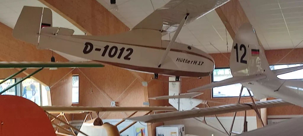 Weißes Segelflugzeug-Modell mit Kennung D-1012 und Modellbezeichnung Hüttter H17, aufgehängt in Innenraum mit Holzwänden