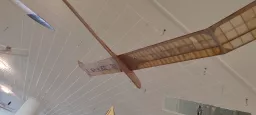 Holz-Segelflugmodell mit Gitterstruktur, von der Decke einer hellen Ausstellungshalle hängend