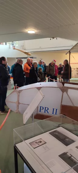 Gruppenbesuch in Ausstellungsraum mit Modellflugzeug PR II, Besucher betrachten Ausstellungsstücke