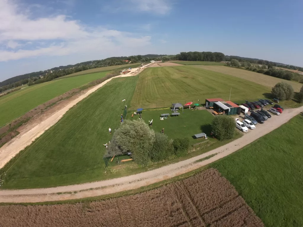 Luftaufnahme eines Modellflugplatzes mit gr&uuml;nen Rasenfl&auml;chen, Parkplatz, Vereinscontainern und Fluggel&auml;nde