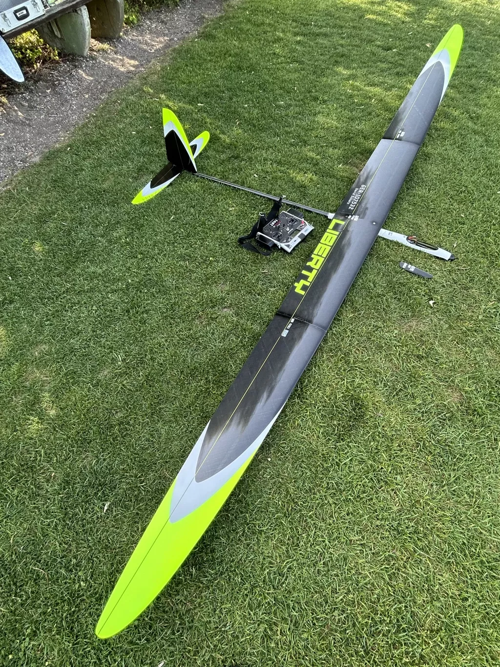 Graues und neongelbes Segelflugmodell mit Fernsteuerung auf gr&uuml;nem Rasengrund, Modelltyp Liberty