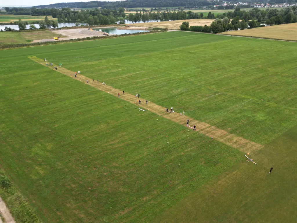 Weite Gr&uuml;nfl&auml;che mit schmalem Modellflugstreifen, im Hintergrund Teiche und Waldhorizont