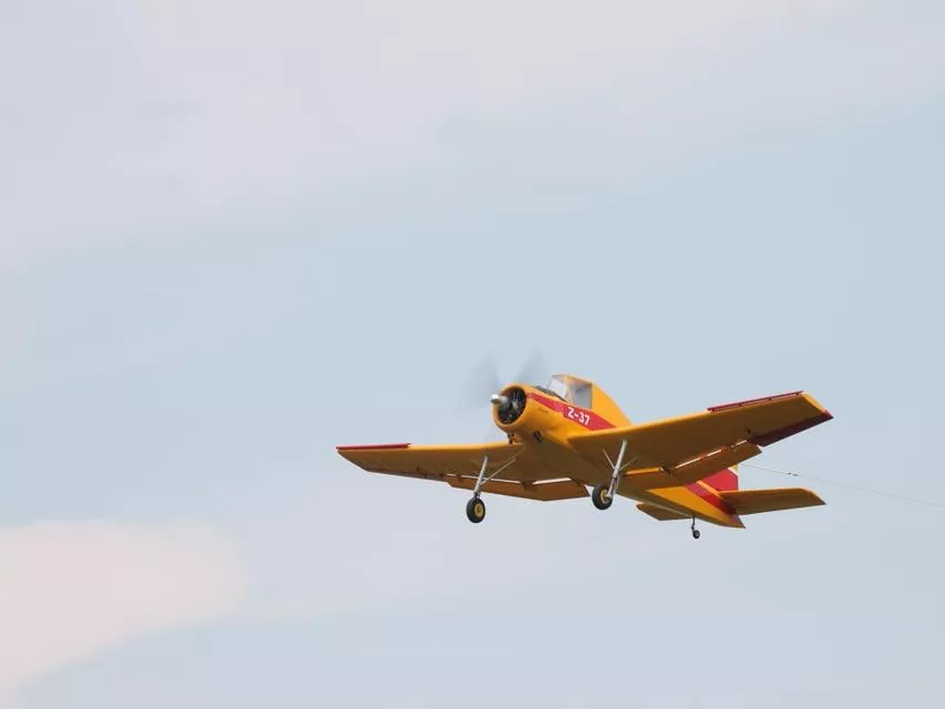 Gelbes Propellerflugzeugmodell mit rot-gelber Farbgebung fliegt vor blassblauem Himmel, Kennzahl Z-37 sichtbar