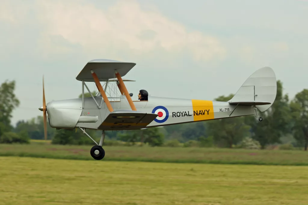 Historischer silberner Doppeldecker-Flugzeugmodell der Royal Navy in Flug &uuml;ber gr&uuml;ne Wiese, Kennzeichen XL-715