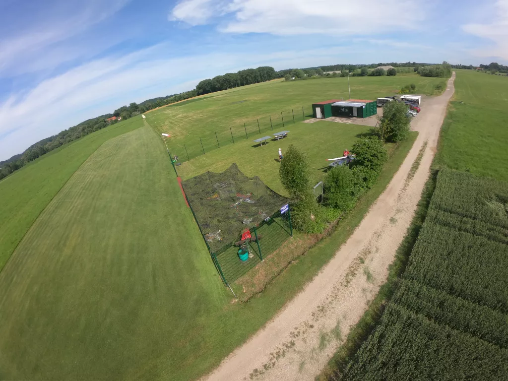 Luftaufnahme eines Modellflugplatzes mit gr&uuml;ner Wiese, Vereinscontainern, Zufahrtsweg und Zaun